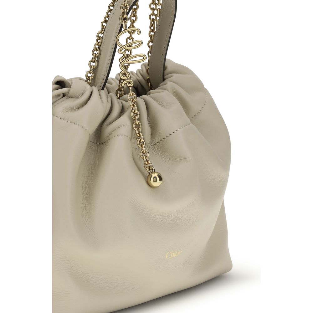 Beige shoulder bag with gold-tone chain and drawstring closure, front view