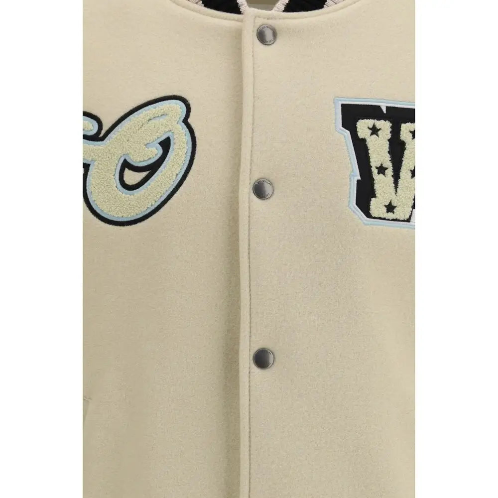 Cream-farvet varsityjakke med broderede bogstaver i sort, lyseblå og off-white på beige uldbomber