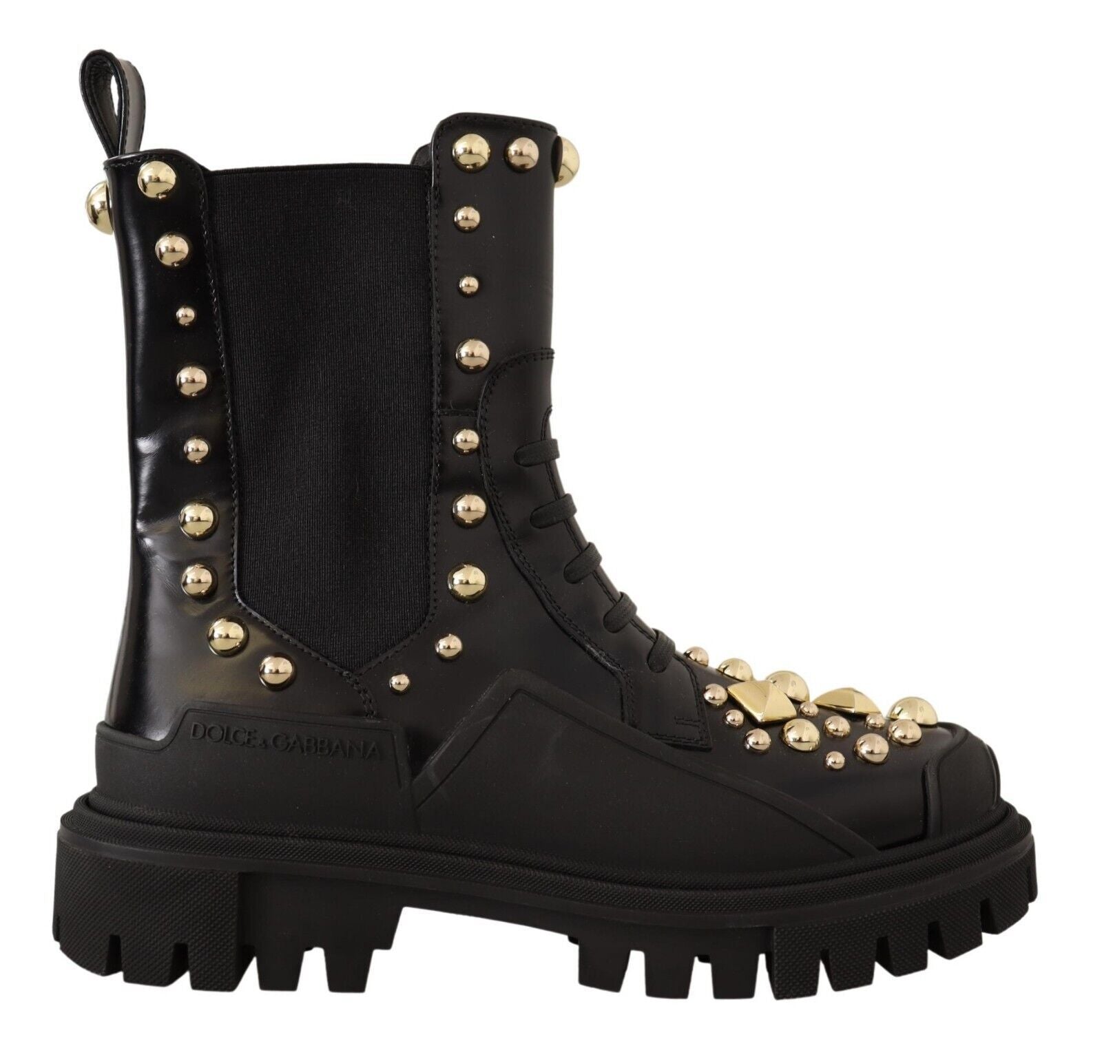 Black boot viewed from the side featuring gold-colored round and pyramid studs and a thick lug sole.