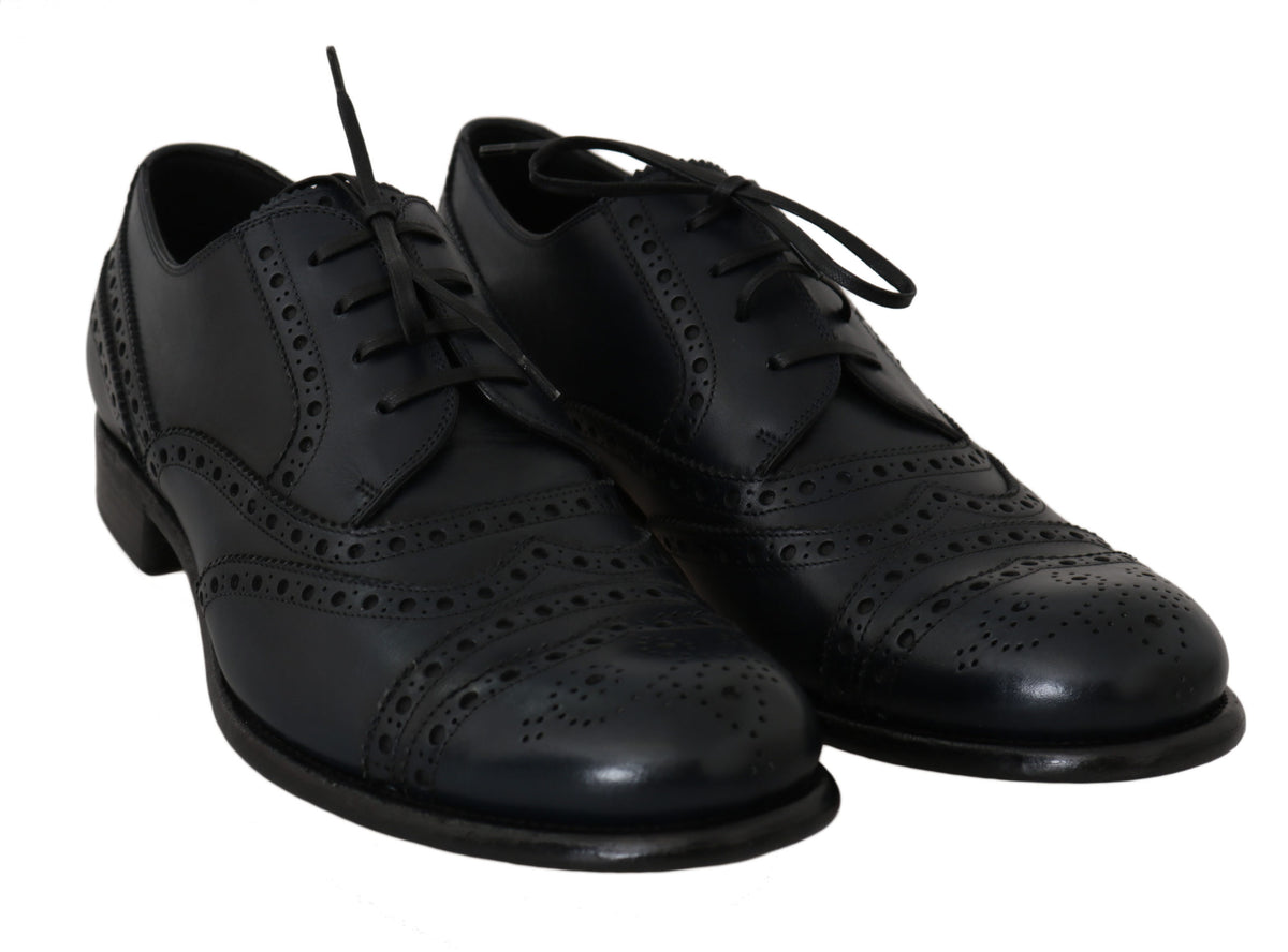 Black lace-up shoes viewed from the front with decorative perforations and pattern details on the uppers.