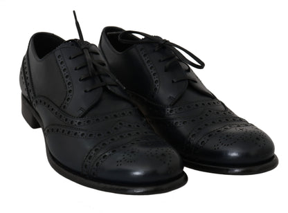 Black lace-up shoes viewed from the front with decorative perforations and pattern details on the uppers.
