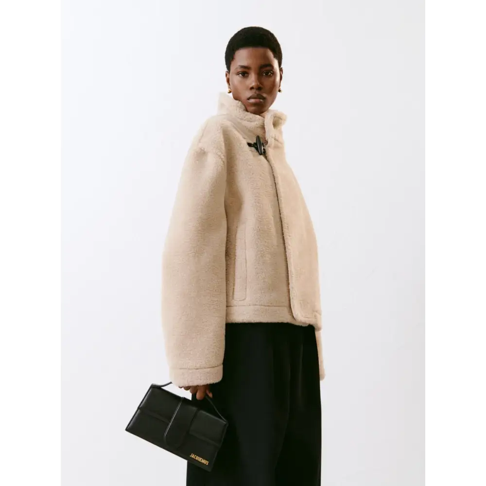 Creamfarvet shearling jakke med høj krave og sorte trykknapper ved Jacquemus black leather le grand grand bambino handbag