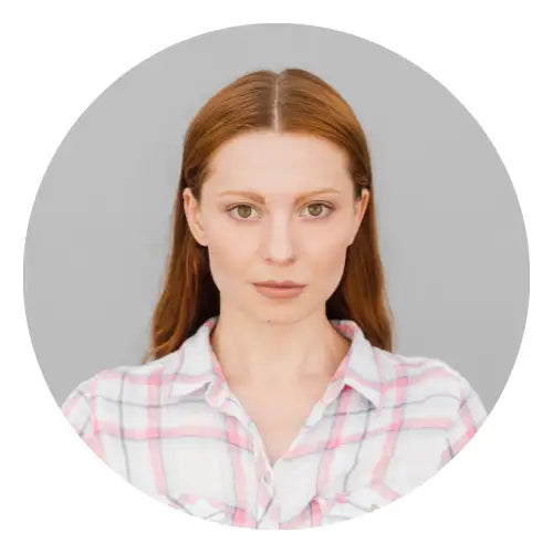 En kvinde med rødbrunt hår iført en lyserød og hvid ternet knapop-skjorte.